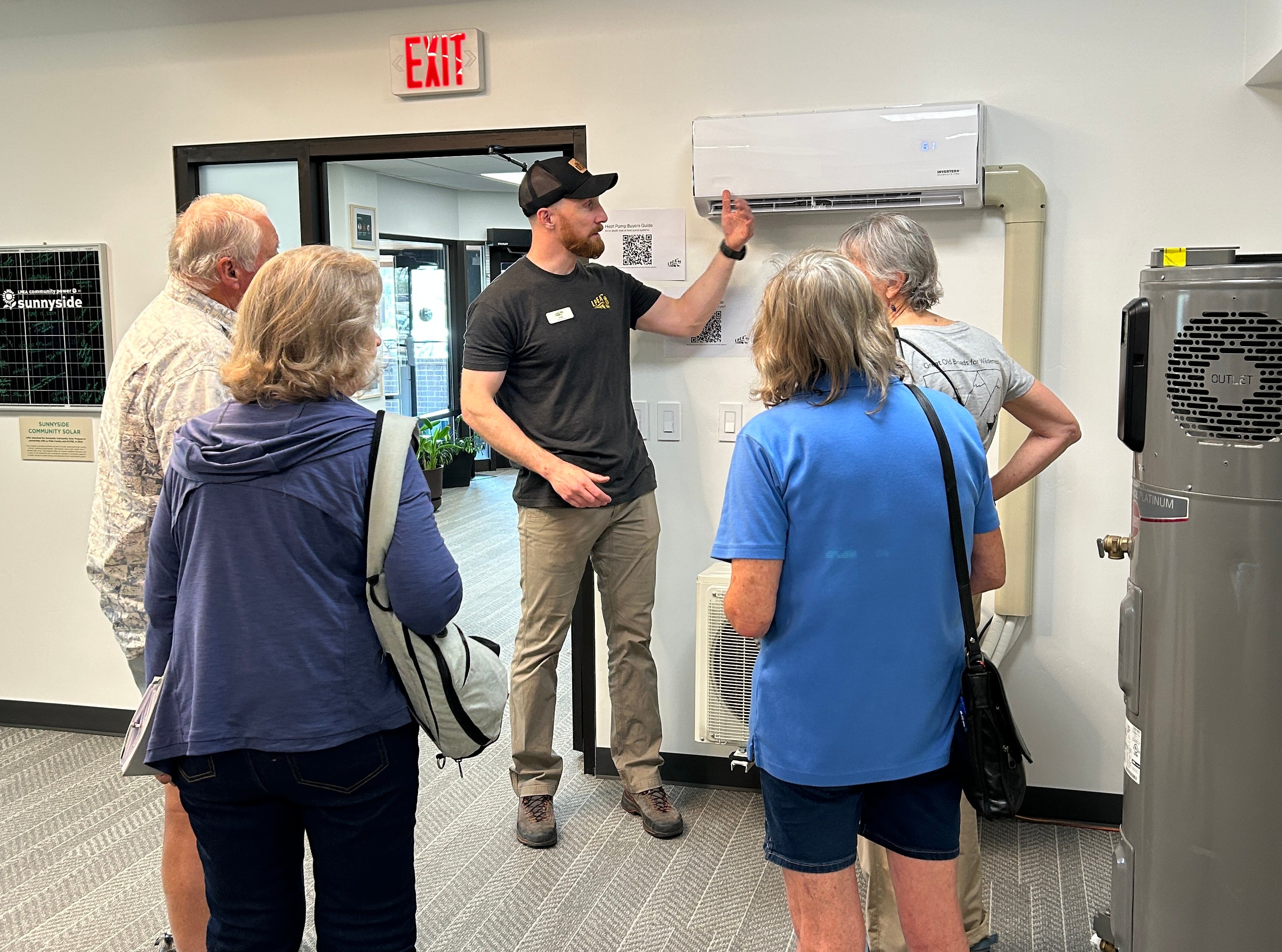 A man demonstrates a heat pump to a group