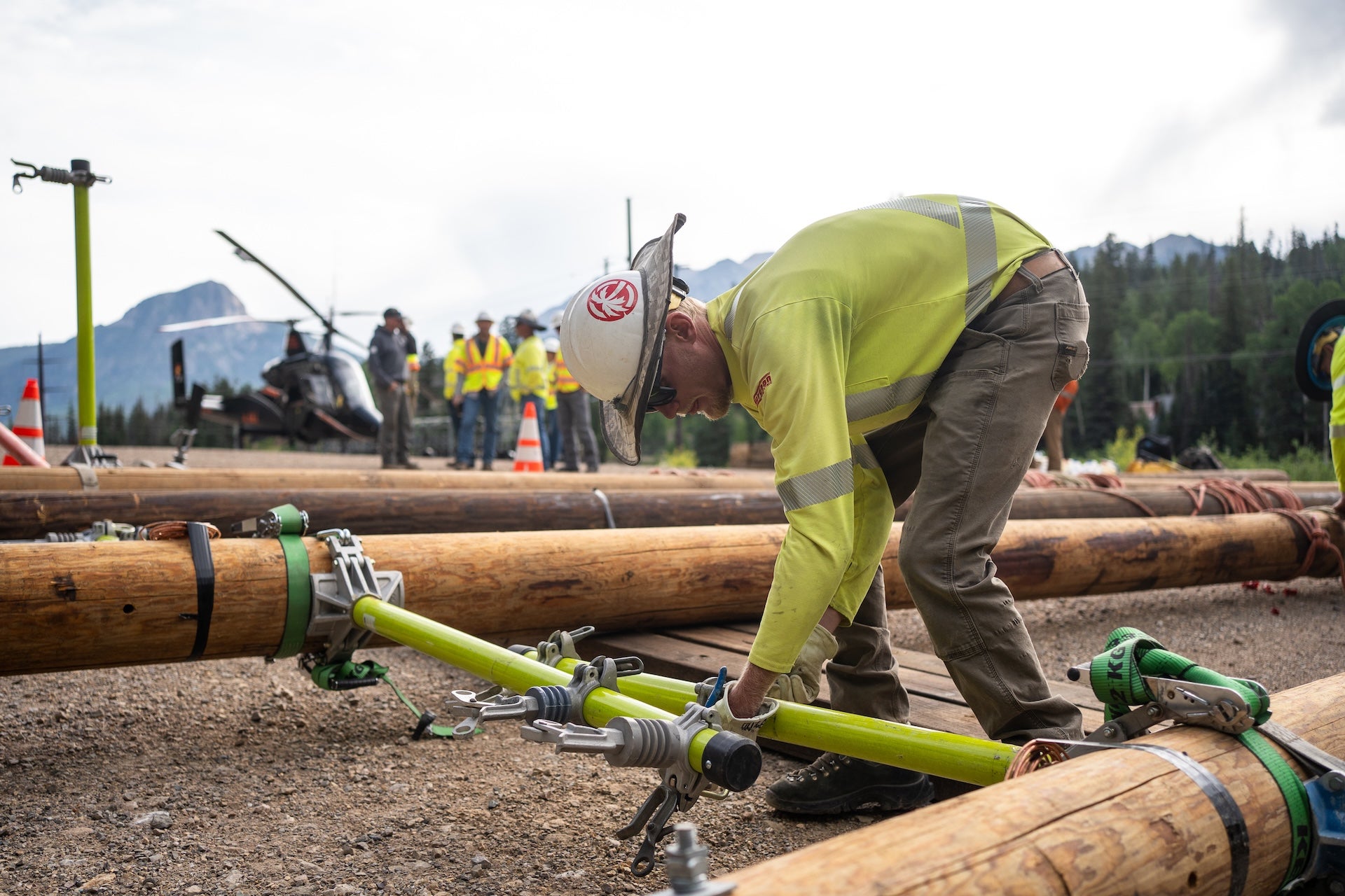 A man in safety gear preps power poles for placement