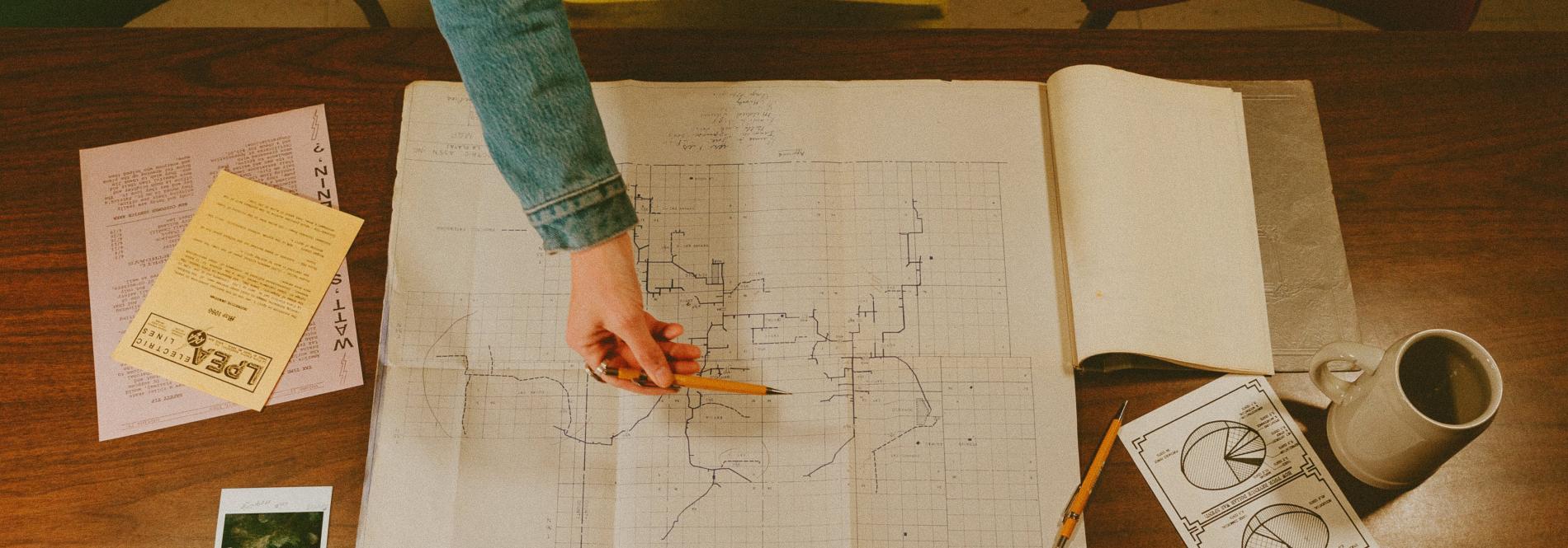 A hand using a pencil to point on a map