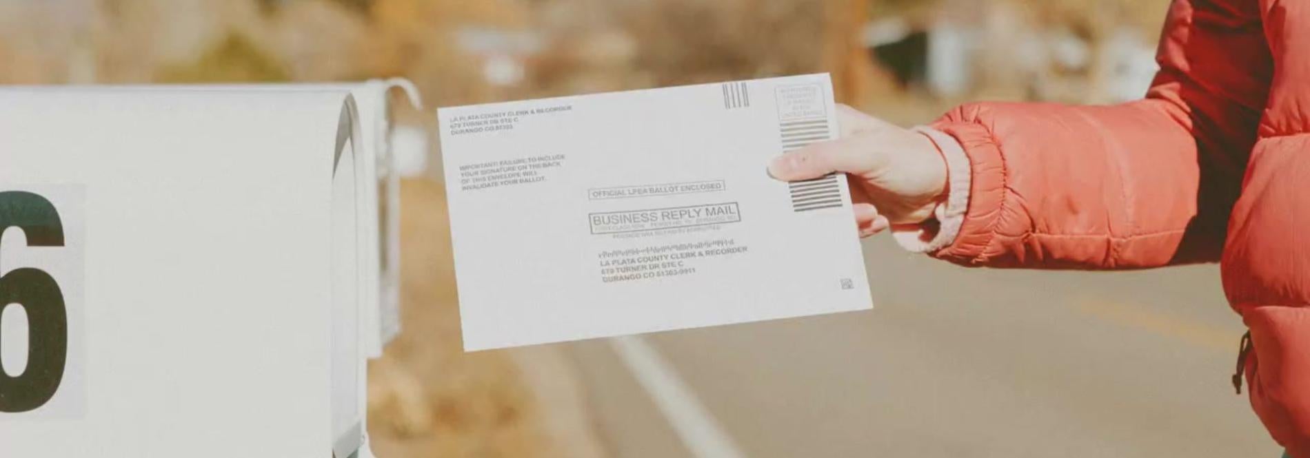 Hand putting a ballot in the mail