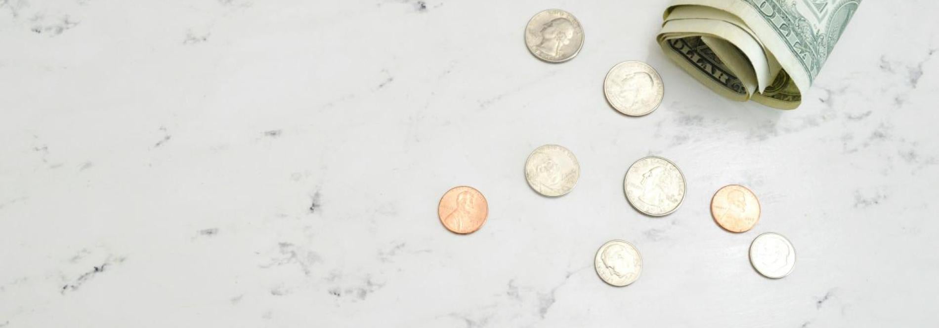 dollar bills and coins on a white marble surface