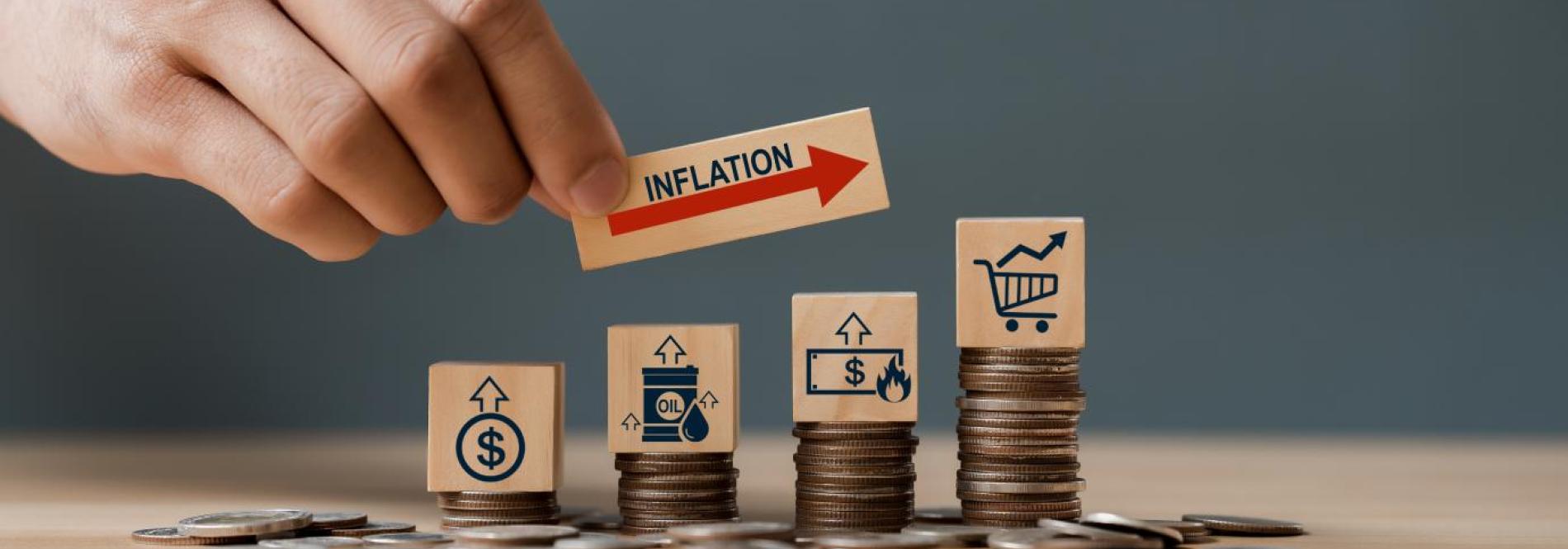 Hand holding blocks with coin stacks to illustrate inflation